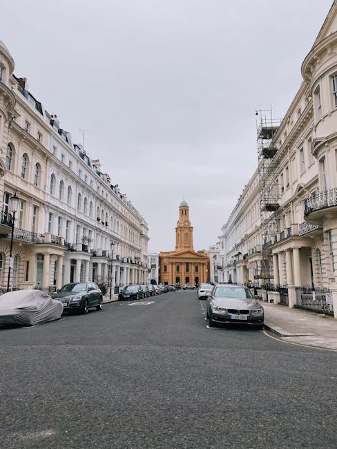 A three-storey, pink-painted residential building with a curved facade and white window frames, situated on a corner of a quiet street in Notting Hill. The ground floor features four visible windows, 