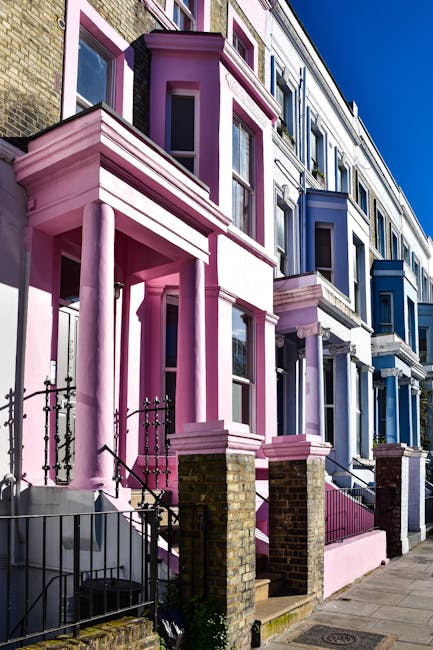 The image shows a row of colourful Victorian terraced houses with detailed architectural features, including large bay windows, decorative cornices, and ornate wooden trims. The houses are painted in
